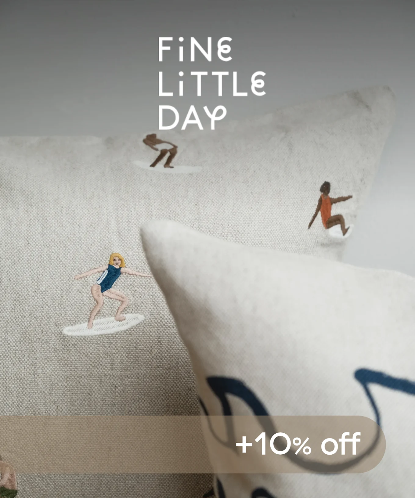 サーファーが刺繍された2つのクッション。1つは青、もう1つはオレンジで、「FiNe LiTTLe DAY」と「+10% off」の文字があります。