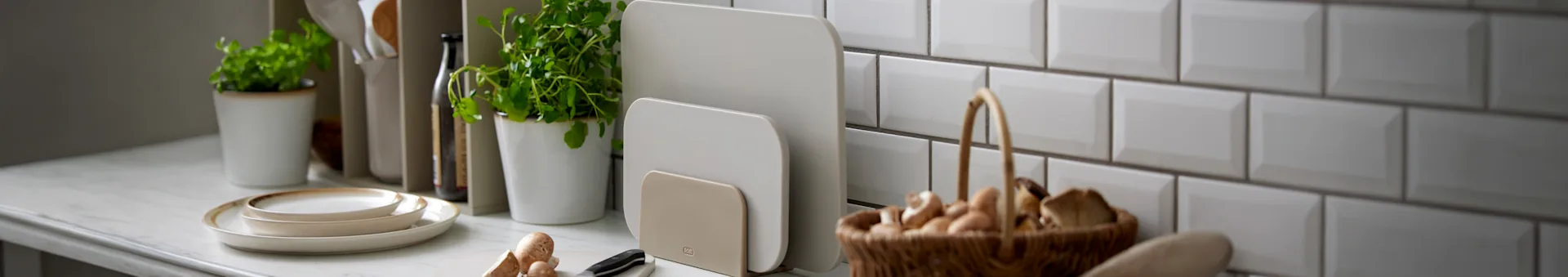 キッチンのカウンターにベージュのまな板が2枚立ててあり、他の調理器具も見える。