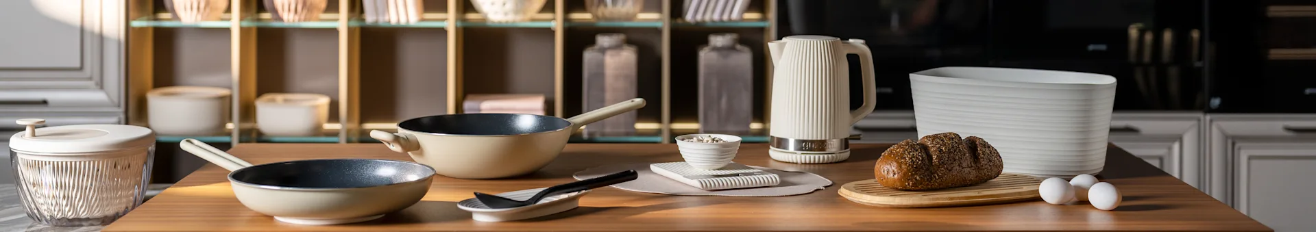 ベージュのフライパン、白いリブ付きケトル、ボード上の種子パン、卵があるキッチンカウンター。モダンなキッチンアクセサリー。