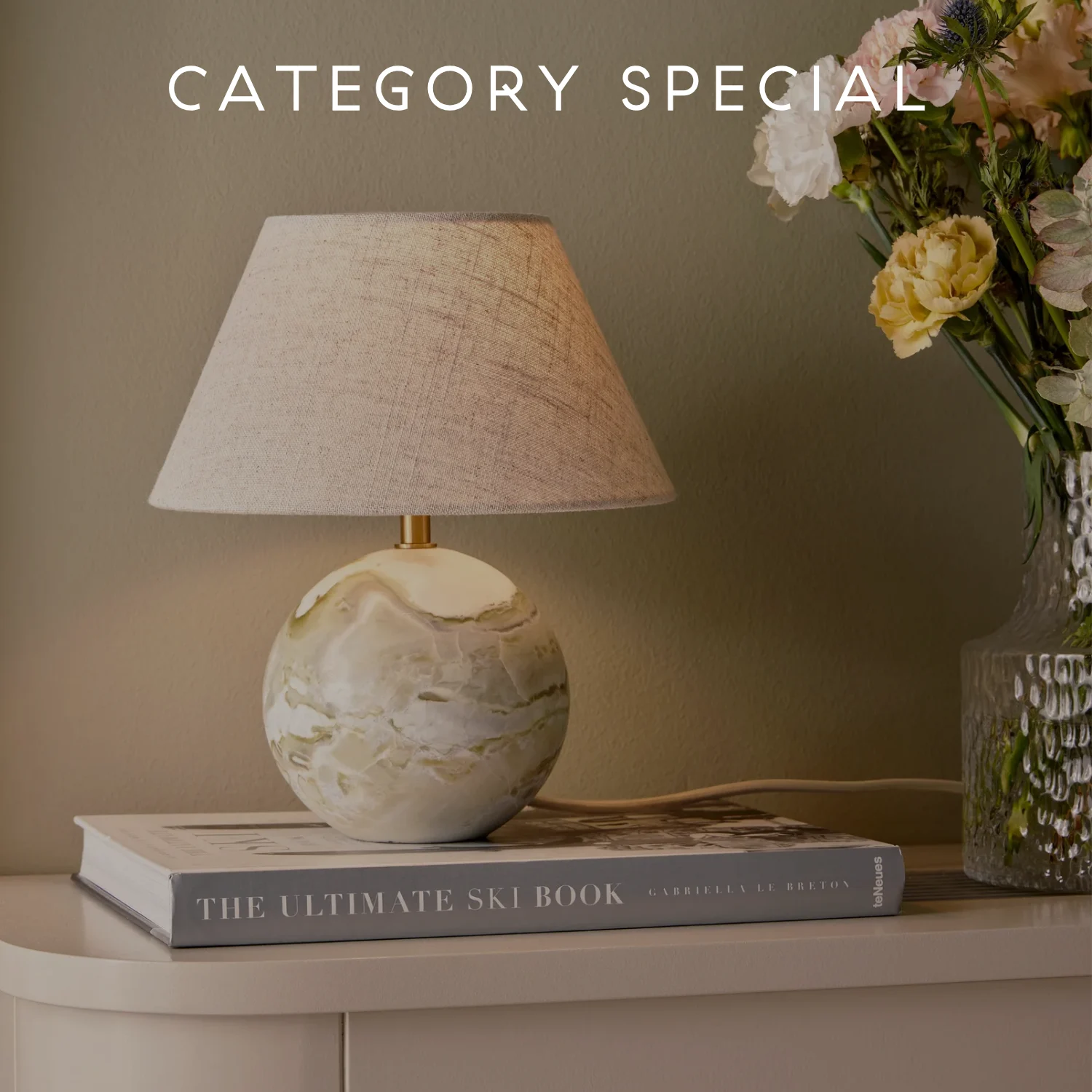 大理石のような球形ベースと明るい布製シェードのテーブルランプ。本の隣に花が飾られ、'CATEGORY SPECIAL'の文字が書かれている。